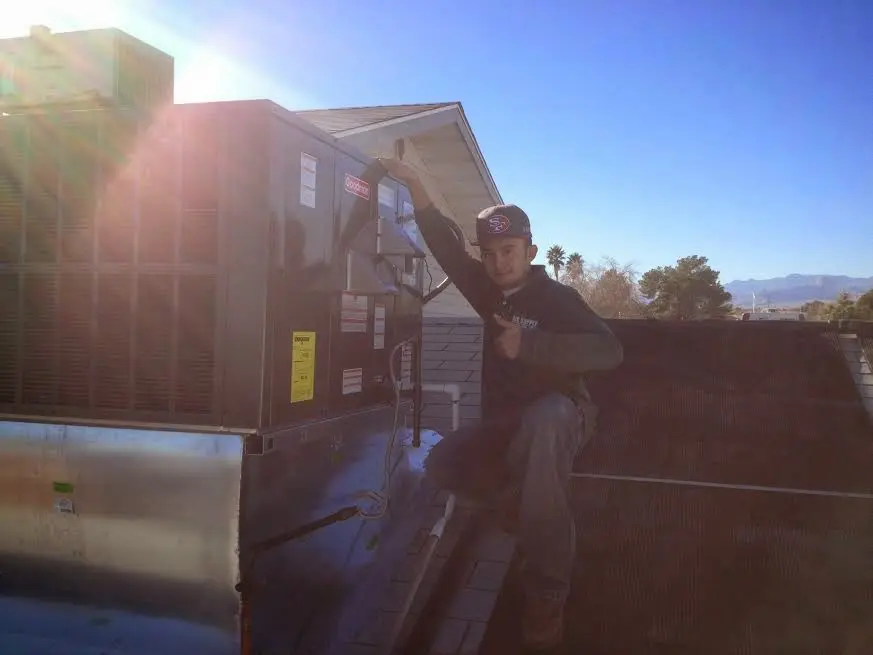HVAC technician performing AC Tune-Up on a rooftop unit in East Hampton